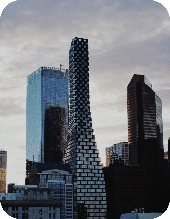 A cityscape at dusk features a unique tower with a twisted design, surrounded by several modern skyscrapers. The sky is overcast, with a blend of gray and blue hues. - Clio Websites | Top Canadian Web Design Company